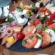 Ein Servierteller mit Lach, Tomate-Mozzarella und Käse, daneben Marmeladengläschen